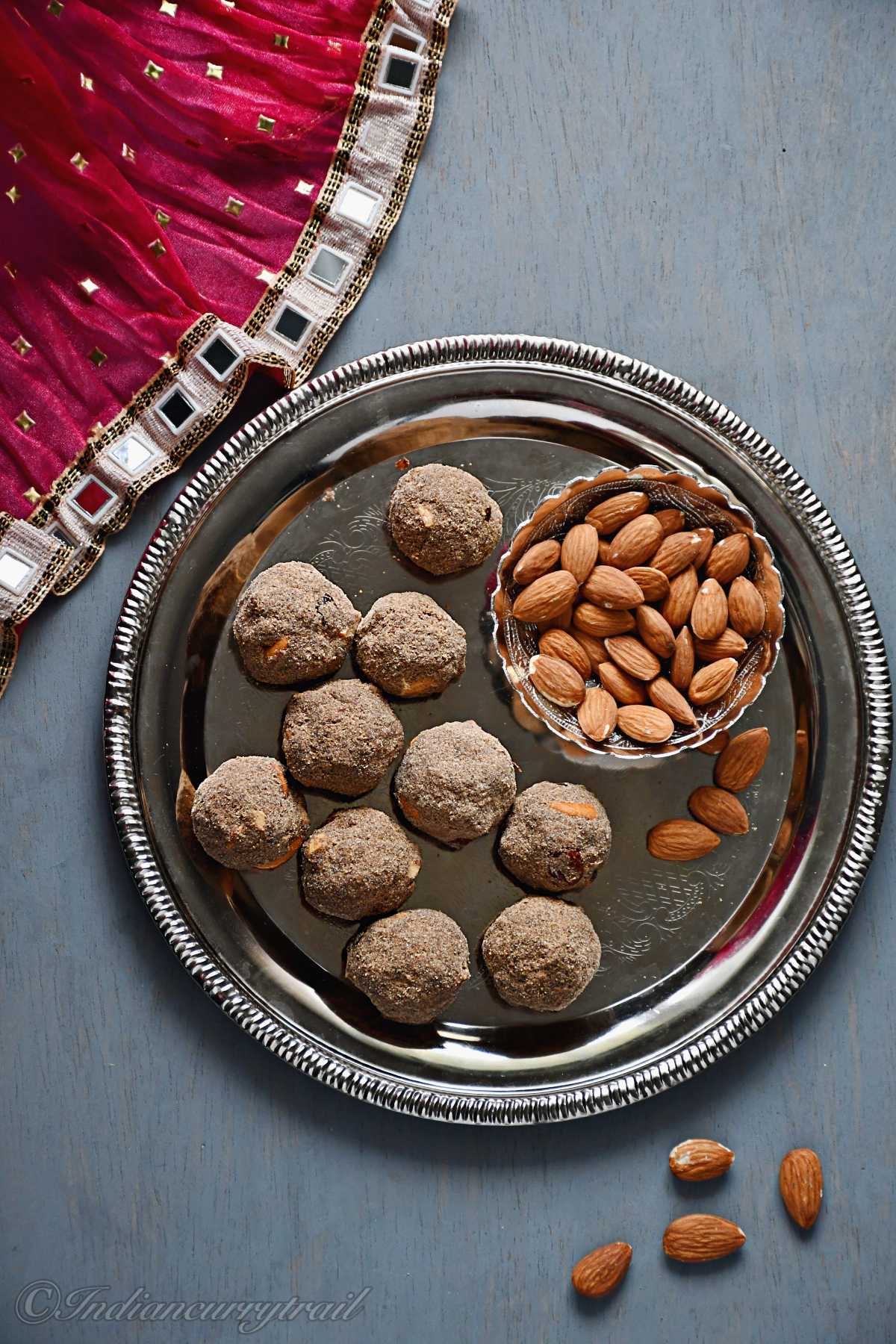 bird eye view of health mix laddu placed on plate with almonds in a bowl