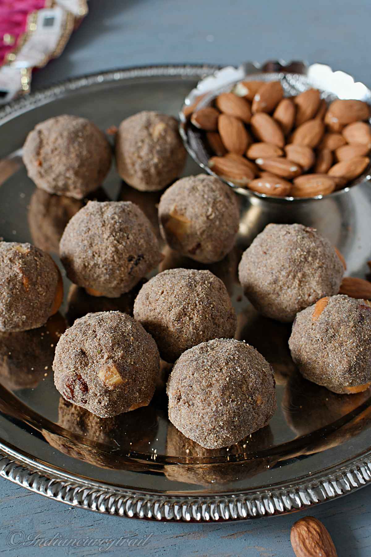 close up view of health mix laddus placed on a plate with a bowl of almond behind