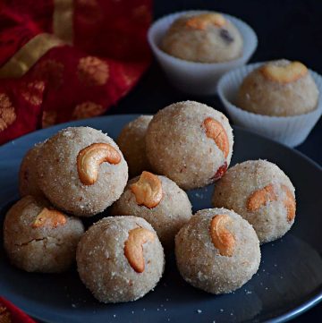 closeup view of rava coconut laddus with cashew nuts kept on a plate
