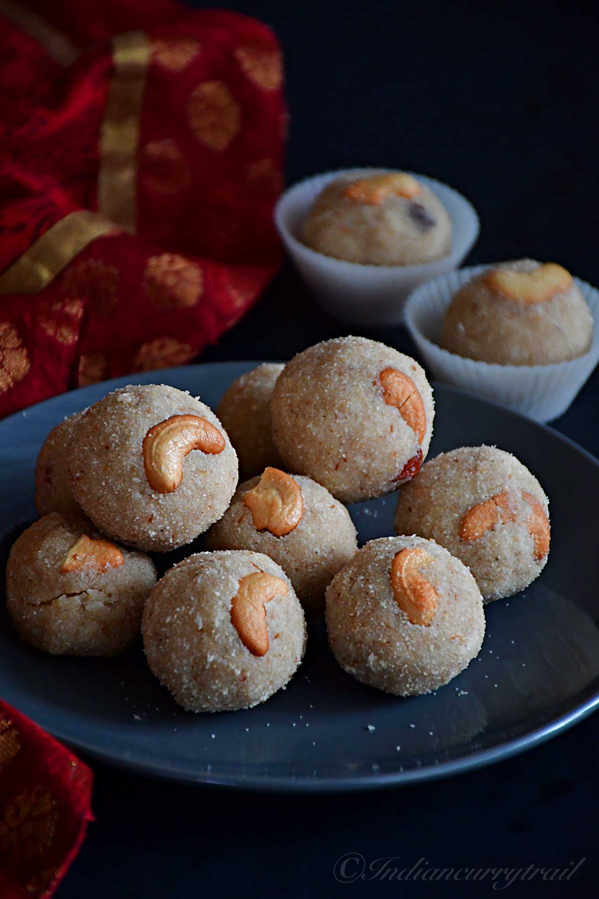 closeup view of rava coconut laddus with cashew nuts kept on a plate.
